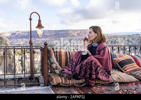 Woman is drinking tea on a balcony in Cappadocia, Turkey Stock Photo