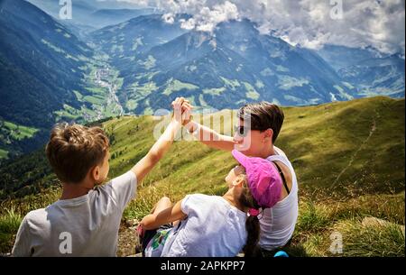 Happy mother with two children having a break from hiking in alpine scenery, Passeier Valley, South Tyrol, Italy Stock Photo