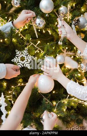 Crop view of children's hands decorating Christmas tree Stock Photo