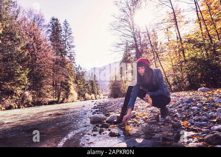 Woman wearing red woolly hat and denim jacket at riverside Stock Photo