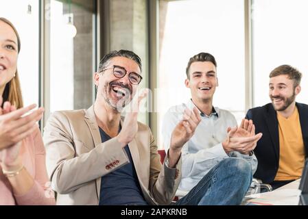 Happy business people applauding during a meeting in boardroom Stock Photo