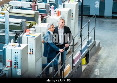 Two businessmen in a printing shop looking around Stock Photo