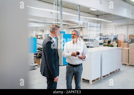 Two businessmen talking in a factory Stock Photo