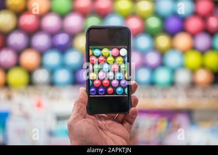 Hnad holding smartphone taking picture of balloons at fairground booth Stock Photo