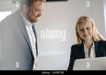 Businessman and businesswoman using laptop in office Stock Photo