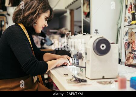 Young fashion designer using sewing machine Stock Photo
