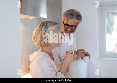Mature couple drinking coffee in kitchen at home Stock Photo