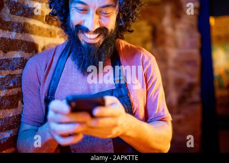Young man, working in bar, using smartphone Stock Photo