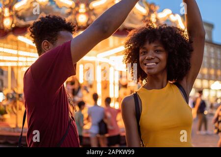 Young tourist couple at an illuminated carousel in the city at dusk, Florence, Italy Stock Photo
