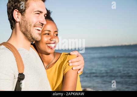 Happy young couple hugging at the waterfront, Lisbon, Portugal Stock Photo