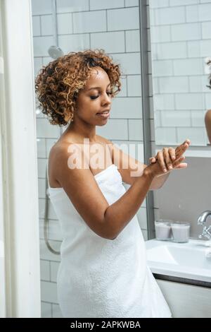 Young woman in bathroom applying hand cream Stock Photo