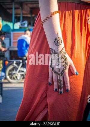 Female in an orange dress with a henna tattoo on her hand in Morocco Stock Photo