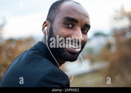 Portrait of smiling young businessman with earphones outdoors Stock Photo