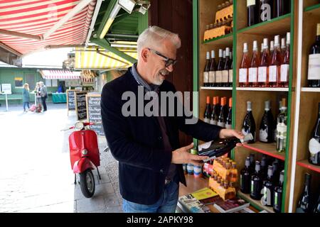 Mature man choosing bottle of wine at a wine shop Stock Photo