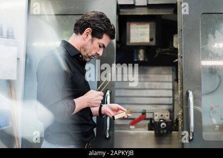 Businessman examining workpiece in a factory Stock Photo