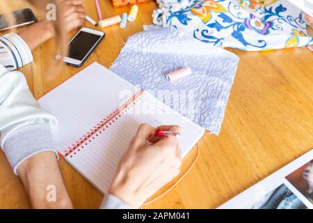 Fashion designer taking noteson desk in office Stock Photo