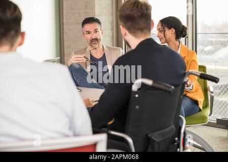 Business people having a meeting in office with one sitting in wheelchair Stock Photo