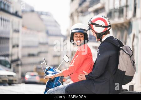 Happy young business couple on motor scooter in the city, Lisbon, Portugal Stock Photo
