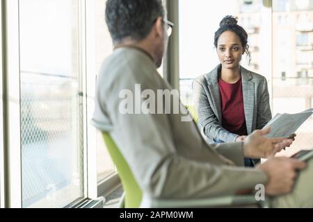 Mature businessman talking to young businesswoman in office Stock Photo