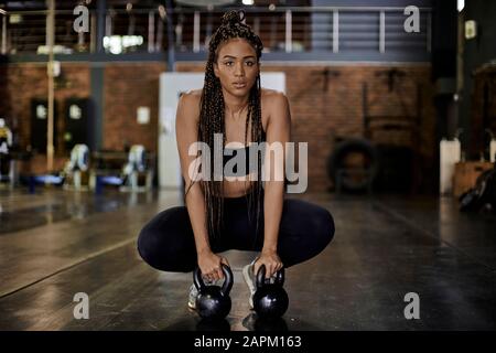 Female athlete training with kettlebells in gym Stock Photo