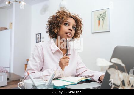 Young woman working at home taking notes Stock Photo