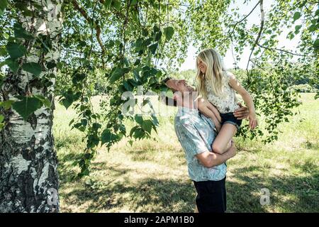 Happy father carrying daughter under a birch tree Stock Photo