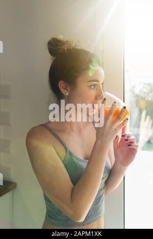 Female teenager drinking juice and looking out of the window Stock Photo