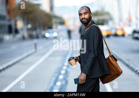 Portrait of young businessman with coffee to go crossing the street Stock Photo