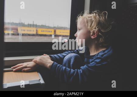 Little boy sitting in train looking out of window Stock Photo