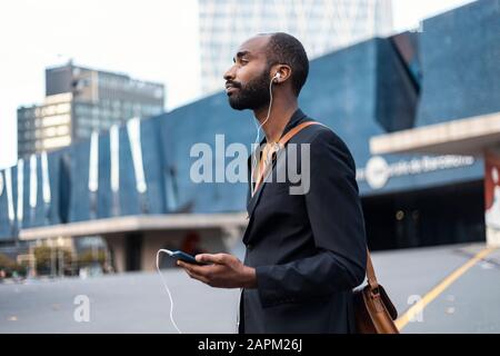 Young businessman with listening music with earphones and smartphone outdoors Stock Photo