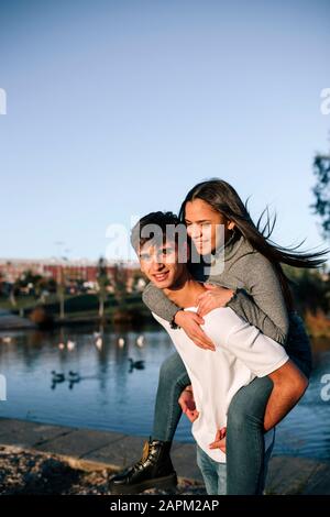 Portrait of happy teenage boy giving his girlfriend a piggyback ride Stock Photo