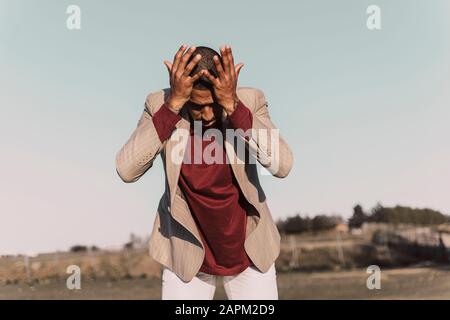 Desperate young man standing outdoors Stock Photo