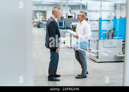Two businessmen talking in a factory Stock Photo