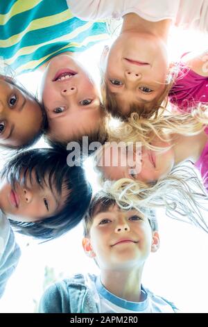 Group of children, sticking heads together, upward view Stock Photo