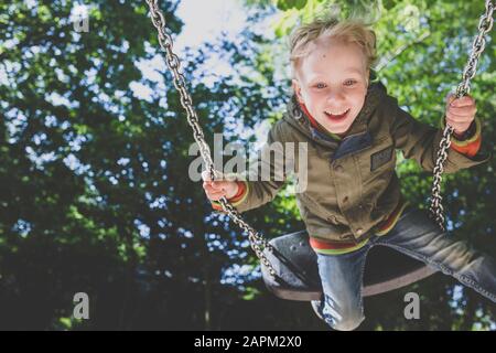 Portrait of happy little boy on a swing Stock Photo