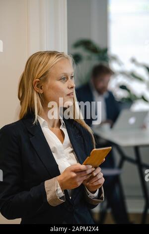 Young businesswoman with cell phone in office Stock Photo