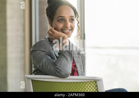 Smiling young businesswoman sitting on a chair in office Stock Photo