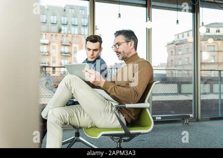 Mature businessman with tablet and young man working in office Stock Photo
