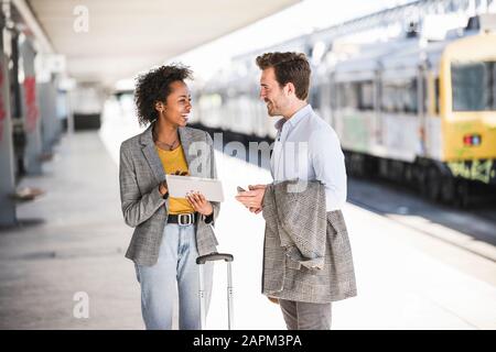 Young businessman and happy businesswoman using tablet together at the train station Stock Photo