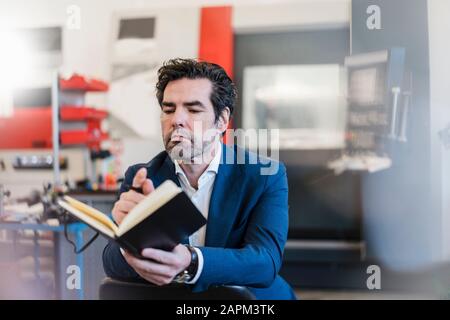 Businessman holding notebook in a factory Stock Photo