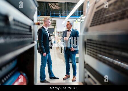 Two businessmen talking in a factory Stock Photo