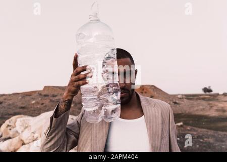 Portrait of serious young man holding empty plastic bottle Stock Photo