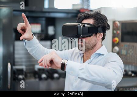 Businessman using VR glasses in a factory Stock Photo