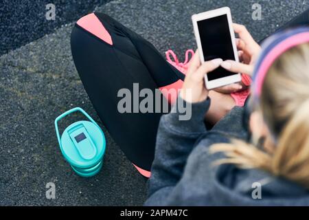 Young woman using smartphone after workout, elevated view Stock Photo