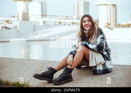 Young brunette woman wearing black and white coat and scarf in the city Stock Photo