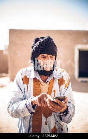 Senior man using cell phone in Smara refugee camp, Tindouf, Algeria Stock Photo