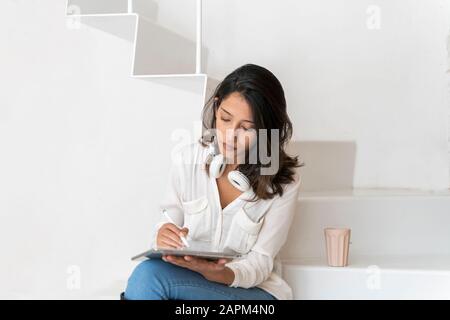 Portrait of young architect sitting on steps in a studio working on tablet Stock Photo