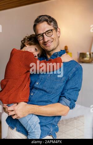 Portrait of smiling father carrying daughter at home Stock Photo