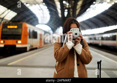 Young woman taking picture with camera at the train station Stock Photo