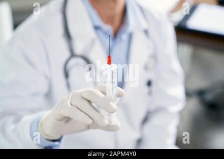 Doctor holding syringe in his medical practice Stock Photo